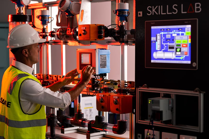 A learner in the Skills Lab laboratory interacts with an HMI on a mock water industry rig setup.  